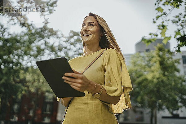 Glückliche Frau mit Tablet-PC an einem sonnigen Tag