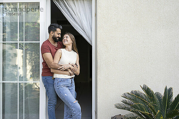 Glückliches Paar  das einander ansieht  während es an der Tür steht