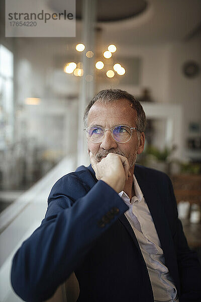 Nachdenklicher Geschäftsmann mit Brille sitzt im Café