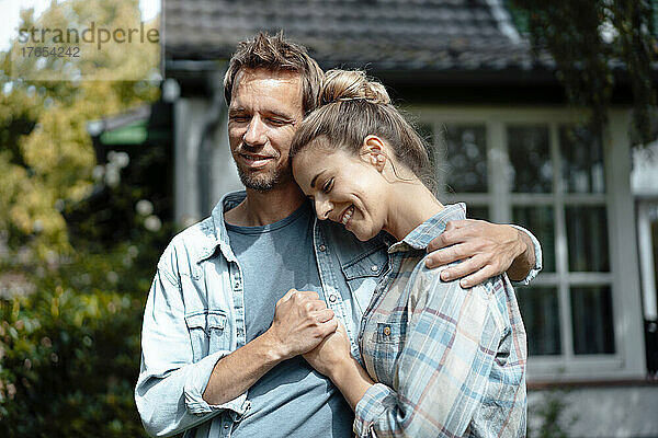 Lächelnder Mann steht mit dem Arm um die Frau im Hinterhof