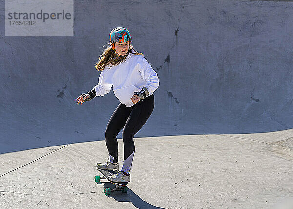 Junge Frau übt Skateboarden auf dem Pumptrack