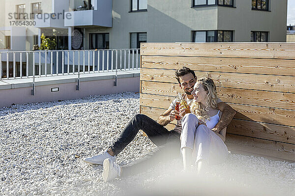 Mann und Frau stoßen gemeinsam auf der Terrasse auf Getränke an