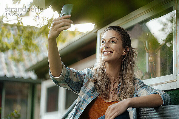 Glückliche Frau  die im Hinterhof ein Selfie mit dem Handy macht