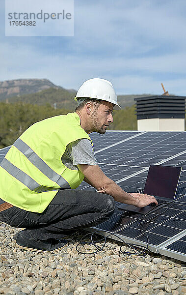 Ingenieur mit Laptop durch Sonnenkollektoren an einem sonnigen Tag