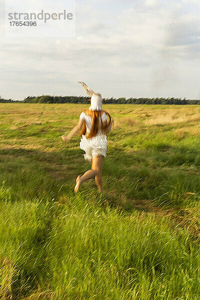 Young woman running on grass field