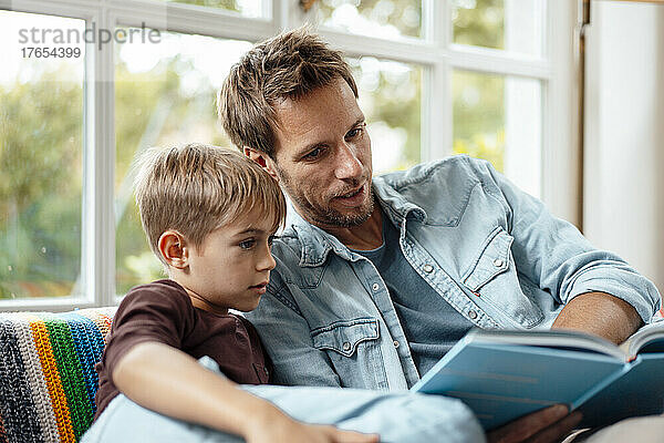 Vater liest seinem Sohn zu Hause ein Buch vor