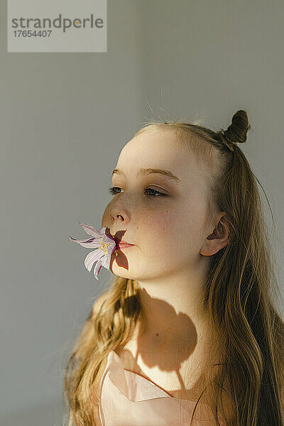 Mädchen hält Blume im Mund