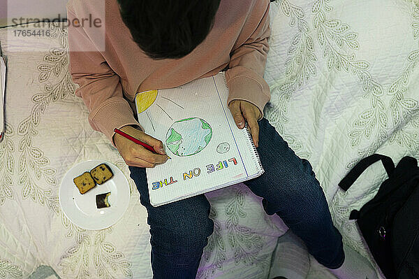 Junge zeichnet zu Hause auf dem Bett