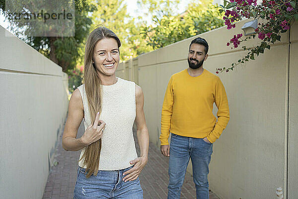 Lächelnde Frau mit langen Haaren neben Mann  der auf Fußweg steht