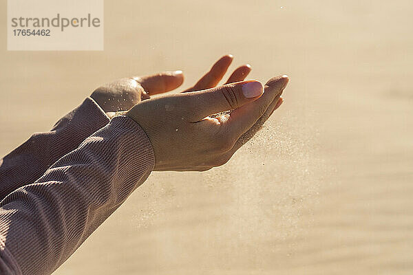 Junge Frau mit Sand in der Hand an einem sonnigen Tag