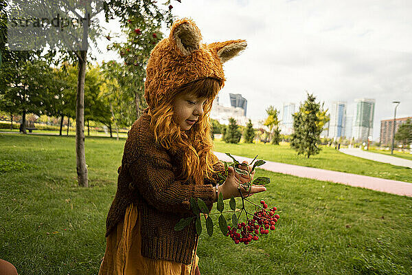 Mädchen hält Beerenfruchtzweig im öffentlichen Park