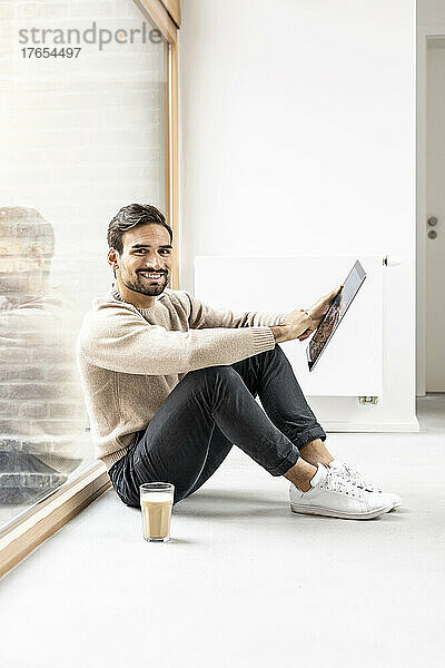 Junger Mann mit Tablet-PC sitzt zu Hause