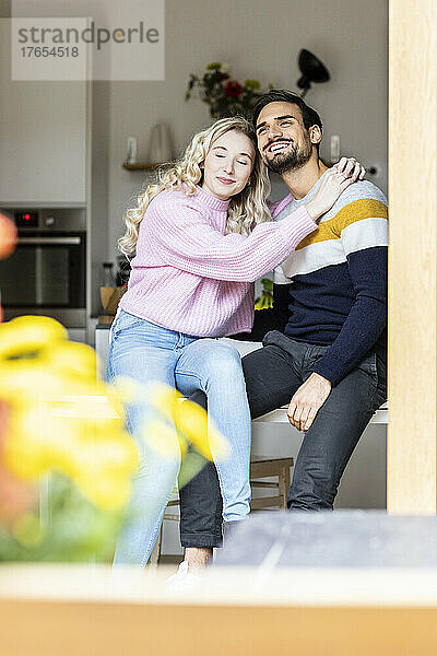 Smiling woman with eyes closed sitting with boyfriend at home