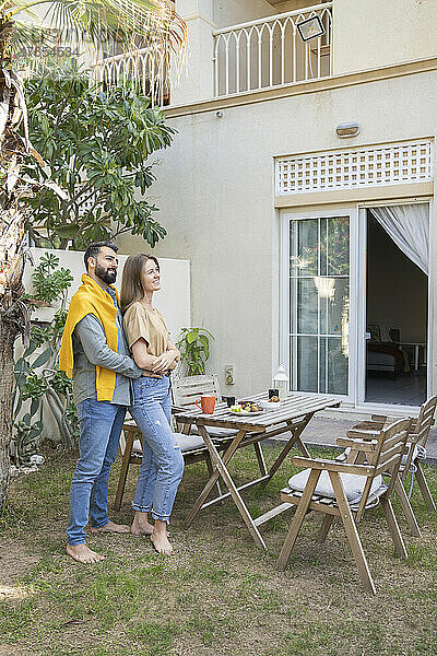 Glückliches Paar steht am Tisch im Garten im Hinterhof