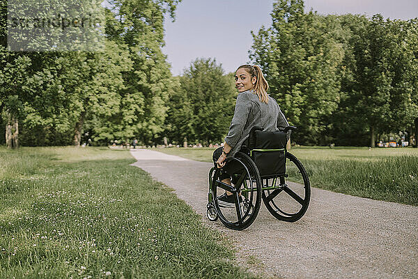 Junge Frau sitzt im Rollstuhl im Park