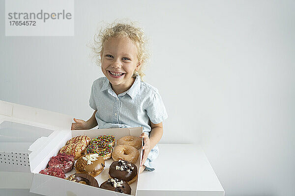 Smiling girl holding box of doughnuts
