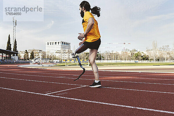 Sportler mit Beinprothese wärmt sich auf der Laufstrecke auf
