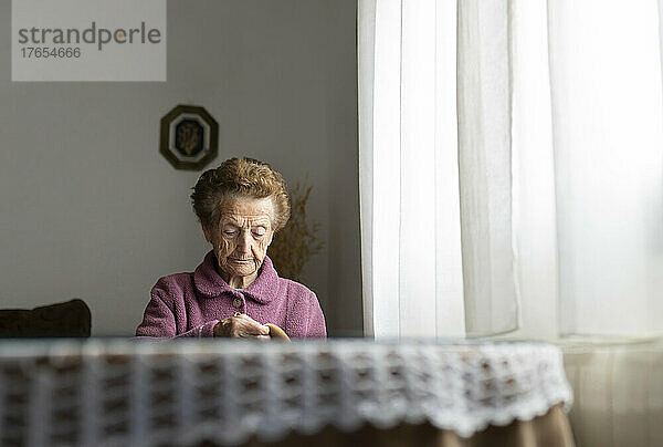 Ältere Frau mit braunen Haaren sitzt am Esstisch