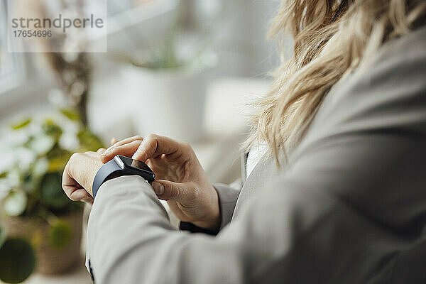 Geschäftsfrau überprüft Smartwatch im Büro
