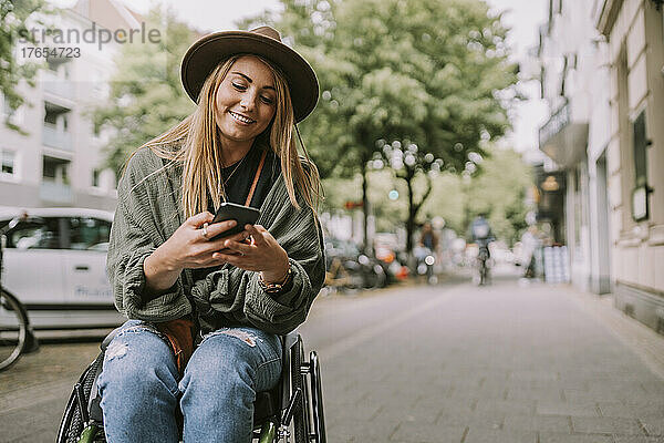 Junge behinderte Frau benutzt Smartphone am Bürgersteig