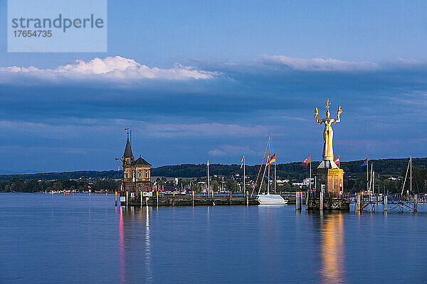 Deutschland  Baden-Württemberg  Konstanz  Hafen am Bodenseeufer in der Abenddämmerung mit Leuchtturm und Imperia-Statue im Hintergrund