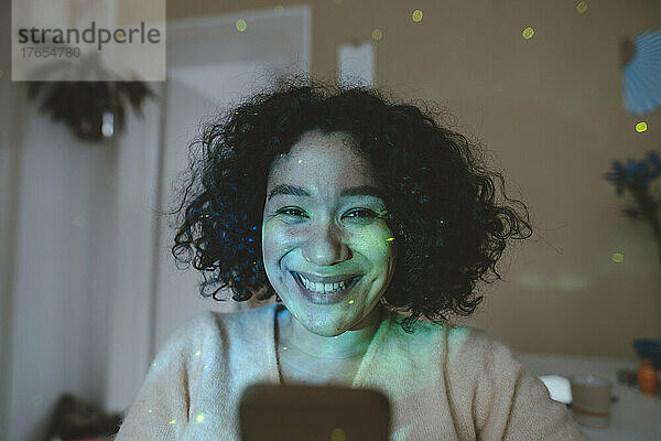 Glückliche Frau mit Astro-Lichteffekten im Zimmer per Smartphone