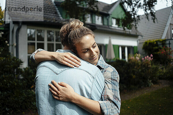 Lächelnde Frau umarmt Freund im Hinterhof