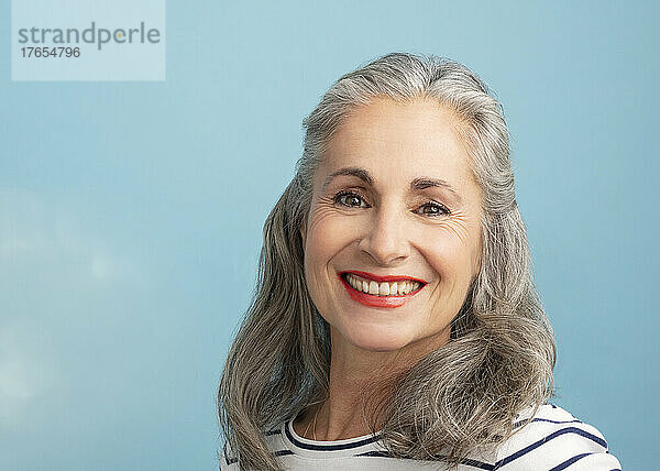 Lächelnde Frau mit grauen Haaren auf blauem Hintergrund