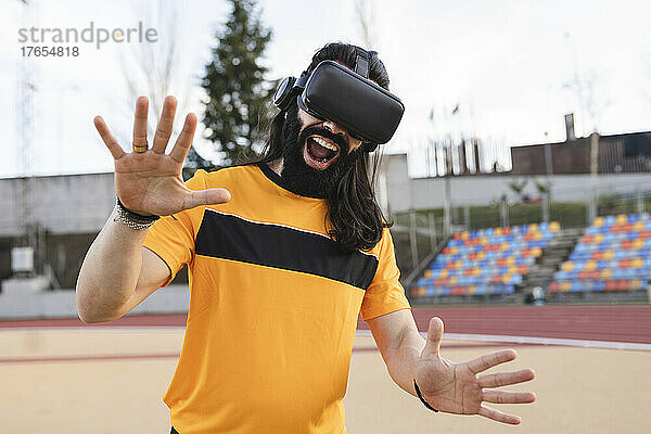 Bärtiger Mann mit Virtual-Reality-Simulator gestikuliert mit offenem Mund