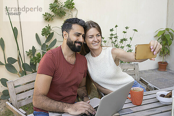 Glückliches Paar macht Selfie mit Smartphone im Hinterhof