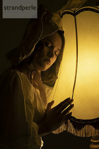 Junge Frau im Kaninchenkostüm mit geschlossenen Augen lehnt an einer Lampe