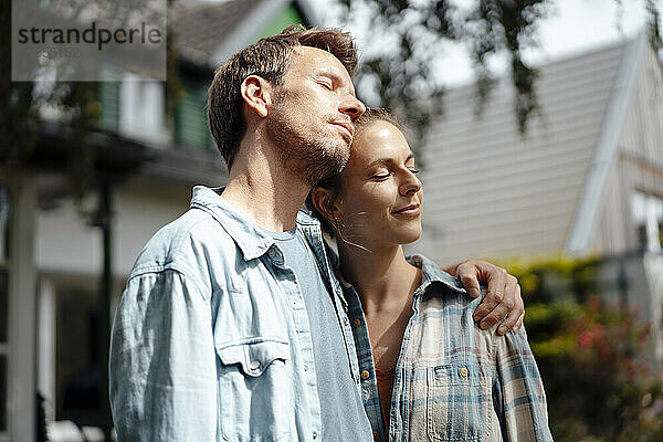 Paar mit geschlossenen Augen genießt den sonnigen Tag im Hinterhof