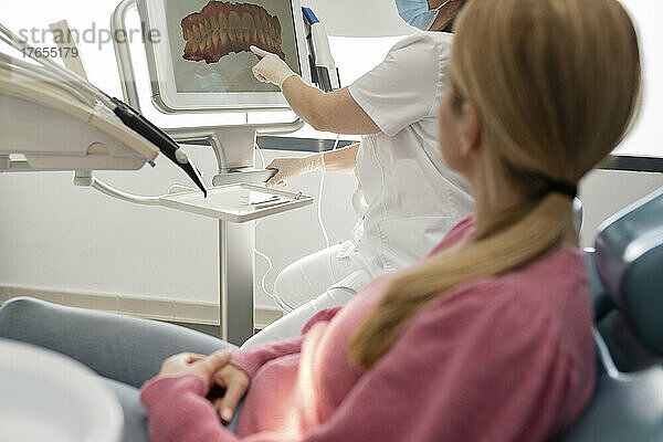Zahnarzt erklärt dem Patienten in der Zahnklinik das Bild der Zähne auf dem Computerbildschirm