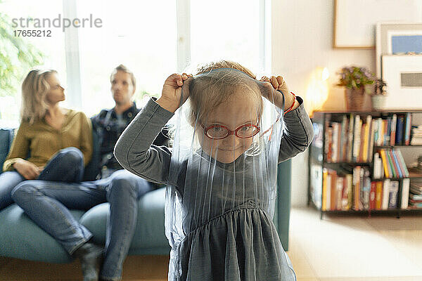 Niedliches kleines Mädchen mit Brille spielt zu Hause im Wohnzimmer