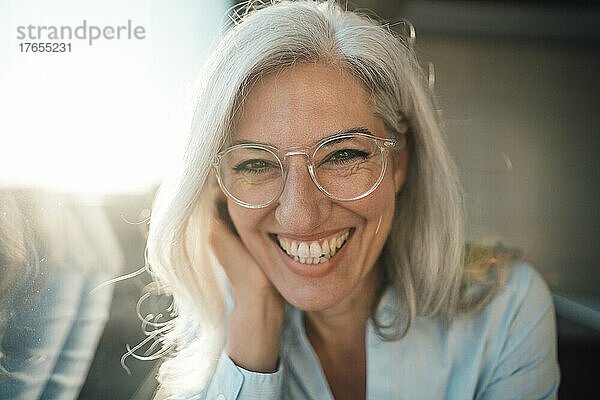 Fröhliche Geschäftsfrau mit grauem Haar und Brille im Büro