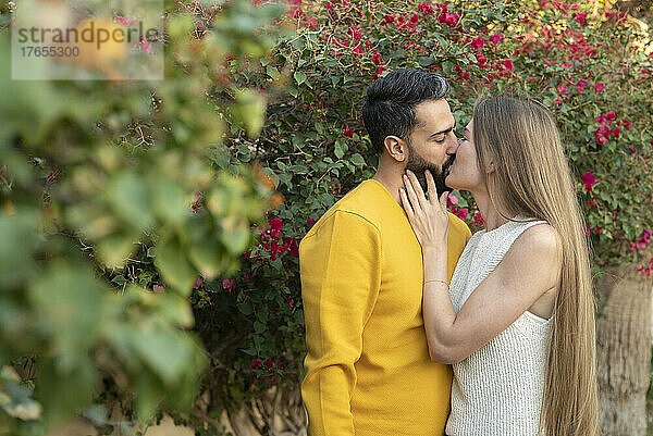 Paar küsst sich neben Pflanzen im Hinterhof