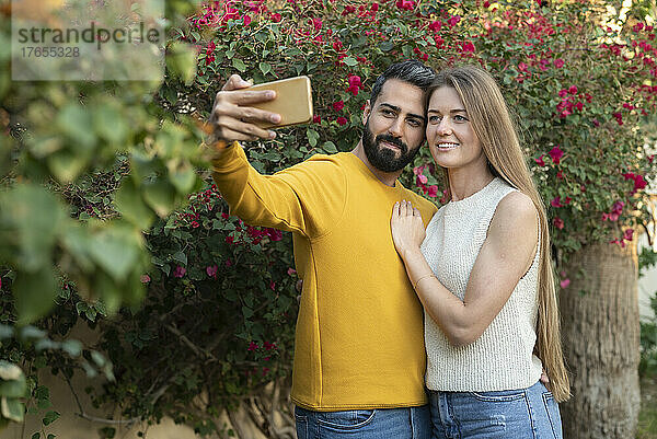 Mann macht Selfie mit Frau per Smartphone im Hinterhof