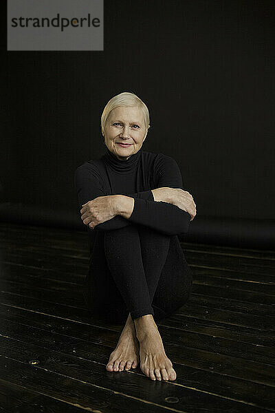 Happy woman with short blond hair sitting against black background