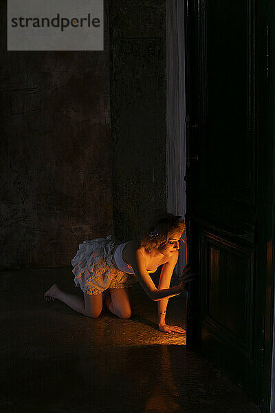 Erleuchtete junge Frau kniet im Dunkeln