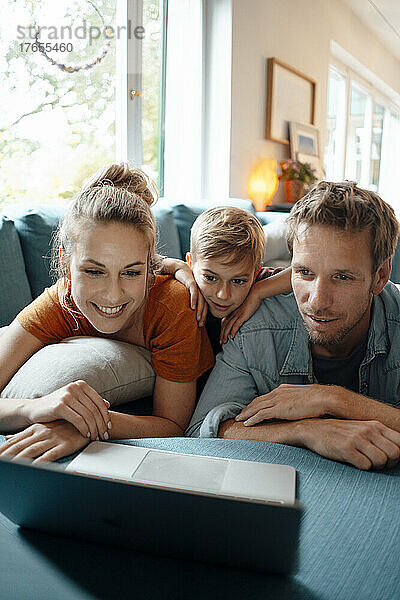 Lächelnde Frau mit Mann und Sohn  die zu Hause ein Video auf dem Laptop ansieht