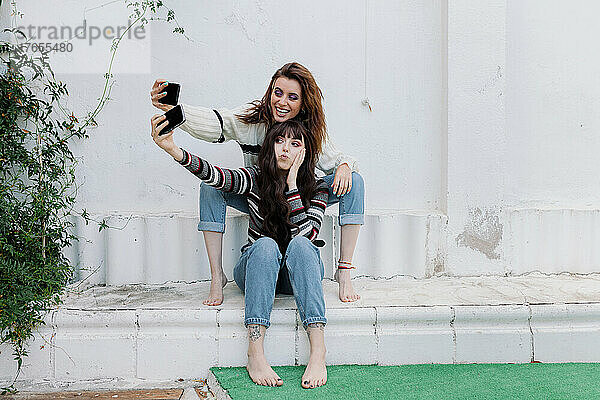 Fröhliche Freunde machen gemeinsam Selfies über Smartphones im Hinterhof