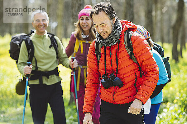 Mann mit Fernglas wandert mit Freunden im Wald