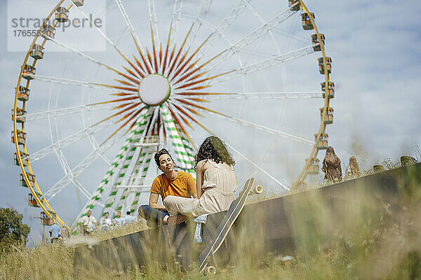 Frau mit Tochter sitzt an sonnigem Tag vor dem Riesenrad