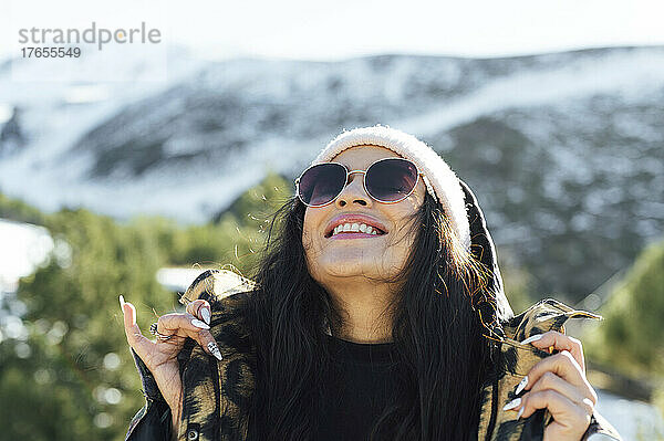 Lächelnde Frau mit Sonnenbrille genießt den sonnigen Tag