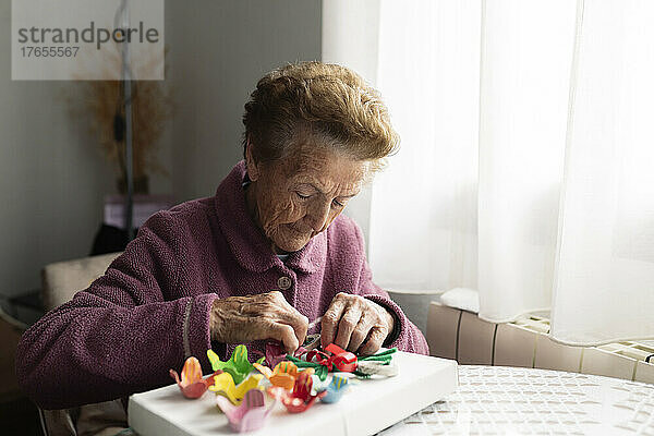 Senior woman making craft sitting at dining table