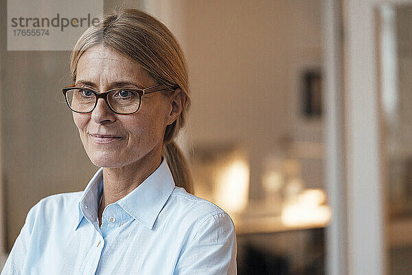 Nachdenkliche Geschäftsfrau mit Brille am Arbeitsplatz