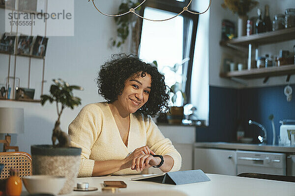 Lächelnde Frau mit Tablet-PC und Smartwatch zu Hause