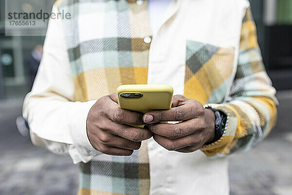 Hand eines Mannes  der Textnachrichten über das Smartphone sendet