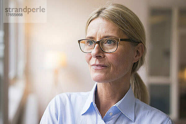 Nachdenkliche Geschäftsfrau mit Brille am Arbeitsplatz