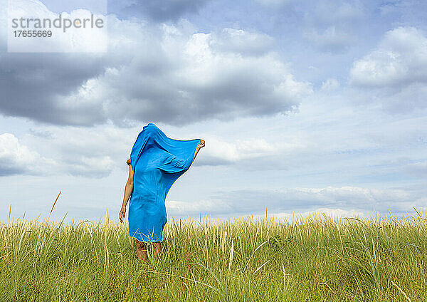 Frau mit blauem Schal bedeckt steht auf der Wiese